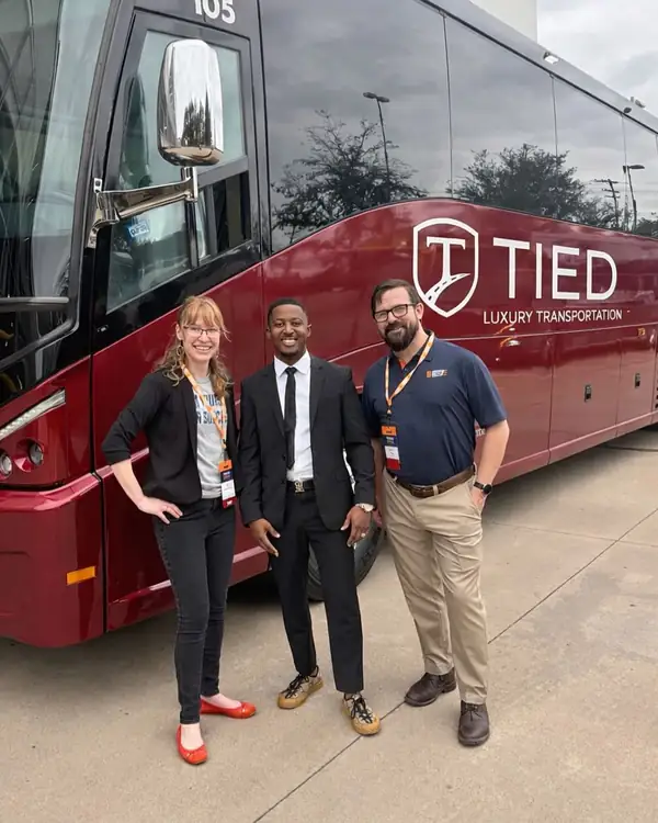 Corporate clients in front of the red TIED LIMO motorcoach